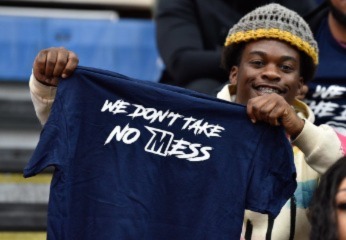 Person holds shirt that says "We don't take no mess".